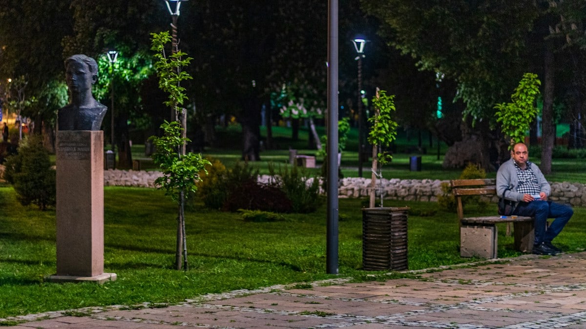 man sitting on bench on park during nighttime